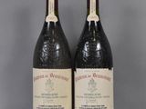 two bottles of wine sit on a table with a gray background
