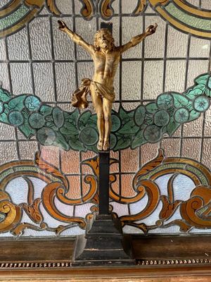 a statue of jesus on a cross in front of a stained glass window