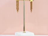 the gold star and chain earrings are on a marble stand