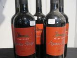 trois bouteilles de vin rouge posées sur une table l'une à côté de l'autre