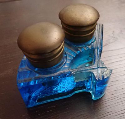 une petite bouteille en verre bleu ornée de deux boutons dorés