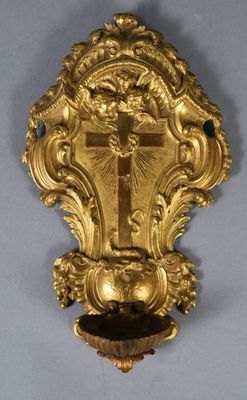 a gold clock hanging on the wall with a cross on it