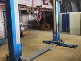 two blue lifts in a garage with a red hose in the background