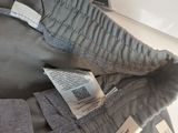 two pairs of grey pants with tags on them sitting on a table
