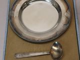 a silver plate and spoon in a box with a spoon