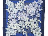 un foulard carré bleu et blanc orné de fleurs blanches