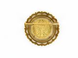 an image of a gold brooch with a coin in the center