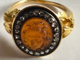 an image of a gold and black ring with a face of a man on it