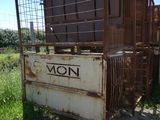 a rusted metal crate with a sign on it in the middle of a field