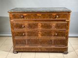 une commode ancienne avec un plateau en marbre, posée sur un sol carrelé