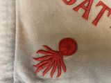 a pillow with a red octopus embroidered on it