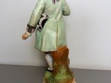 figurine of a man in a green coat with a dog on a leash