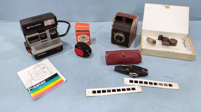un appareil photo Polaroid, un appareil photo Polaroid à pellicule, une règle et d'autres objets posés sur une surface bleue