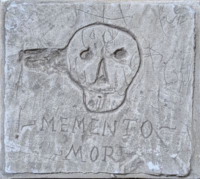bloc de béton sur lequel sont gravés un crâne et des mots