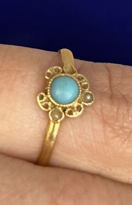 Quelqu'un tient une bague en or sertie d'une turquoise.