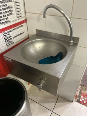 un lavabo en acier inoxydable et une poubelle dans des toilettes publiques