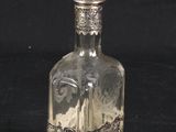 a glass bottle with a silver lid on a black background