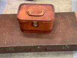 a brown suitcase sitting on top of a brown piece of luggage
