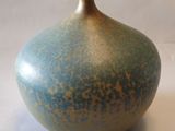 un vase bleu et brun posé sur une surface blanche