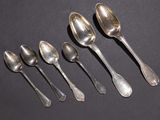 six spoons are lined up in a row on a black surface