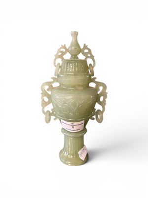 a green vase that is sitting on a white surface