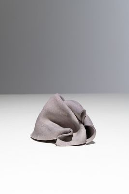 un tissu gris posé sur une surface blanche, sur fond gris