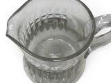 a clear glass pitcher with a handle on a white surface