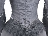 the back of a woman ' s black jacket with fringes on a mannequin mannequin dress