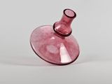 a pink glass vase sitting on top of a white table