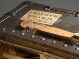 an old suitcase with a leather strap on top of it