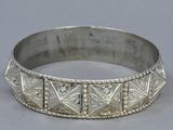 a close up of a silver bracelet on a gray surface