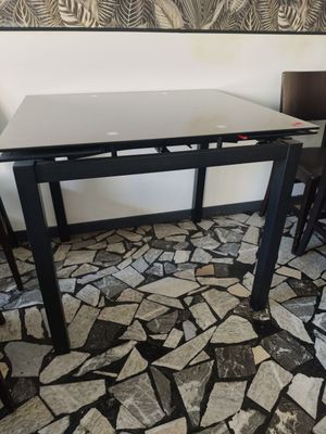 une table et des chaises dans une pièce, avec un tableau accroché au mur derrière elles