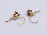 two pairs of gold and ruby earrings on a white surface