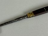 a close up of a knife on a white surface with a black handle