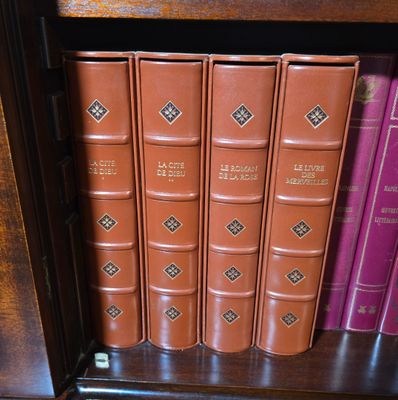 des livres sur une étagère dans une bibliothèque, surmontée d'une horloge