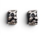 une paire de boucles d'oreilles noires et argentées posées sur une surface blanche