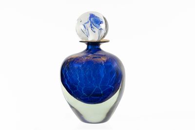 une bouteille en verre bleue avec un fond blanc et un motif bleu et blanc