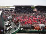 une foule nombreuse dans un stade, brandissant des drapeaux rouges