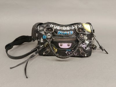 Le sac à main est noir et est orné de nombreuses breloques.