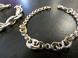 two silver bracelets on a black table with a silver chain