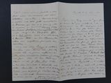 une vieille lettre manuscrite, posée sur un bout de papier, sur une table
