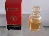 un petit flacon de parfum à côté d'une boîte rouge