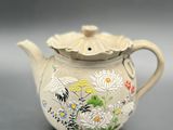 a white tea pot with a floral design on it