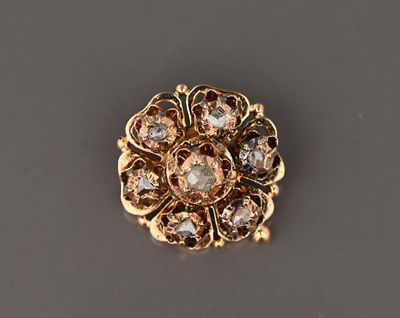 a close up of a gold and diamond broochle on a gray surface