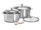 trois casseroles en acier inoxydable avec leurs couvercles et des cuillères en bois, posées sur un plan de travail blanc