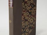 an old book with a decorative cover on a white surface