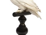 un hibou blanc perché au sommet d'un socle noir