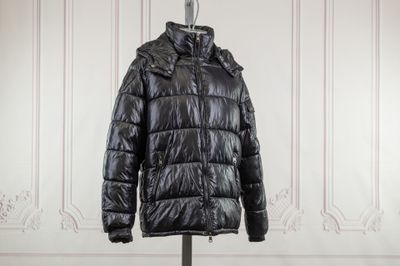 the black jacket is hanging on a hanger in front of a white wall