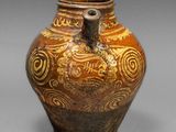 un vase marron orné de motifs, posé sur une table