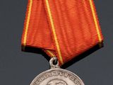 an old medal with a red ribbon on a black surface